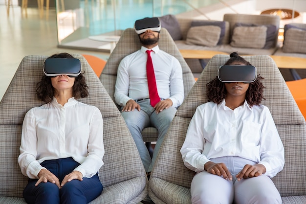 A group of diverse professionals wearing VR headsets in a modern office setting. They are collaborating on a virtual whiteboard displaying complex data visualizations, with annotations and interactive elements. The scene highlights the potential for enhanced collaboration and productivity using metaverse technologies in a business environment.