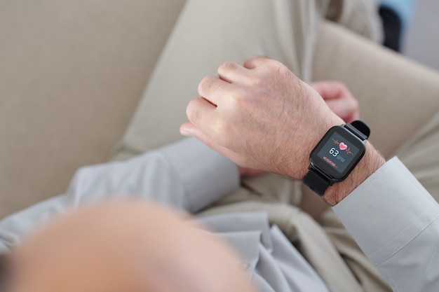 A close-up shot of a smartwatch on a patient's wrist, displaying real-time heart rate and activity data, connected wirelessly to a smartphone, symbolizing remote patient monitoring and data collection in US healthcare.