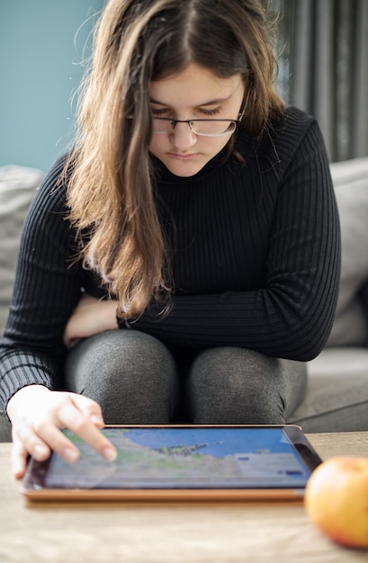A student with a visual impairment using a tablet with AI-powered screen reading software in a classroom setting. The tablet is displaying educational content, and the student is wearing headphones. The scene highlights how AI can provide accessibility and support for students with special needs, allowing them to participate fully in the learning process.