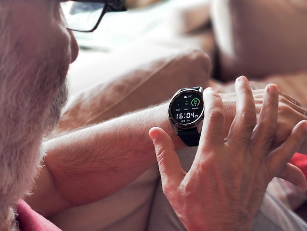 A close-up of a person wearing an at-home sleep apnea testing device on their wrist, showing the display screen with readings of oxygen levels and heart rate.