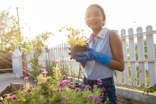 A person happily gardening in their backyard, surrounded by plants and flowers. They are wearing gardening gloves and using a trowel to plant seedlings.