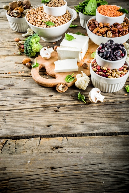 A close-up shot of a variety of plant-based protein sources arranged on a rustic wooden surface. Visible are lentils, quinoa, chia seeds, almonds, and edamame. The focus is on the textures and colors of the different ingredients, highlighting their natural appeal.