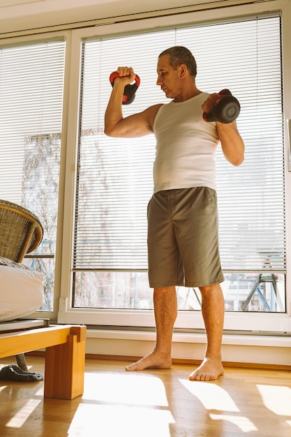 A person lifting dumbbells in a focused manner, performing a bicep curl with proper form in a home setting.
