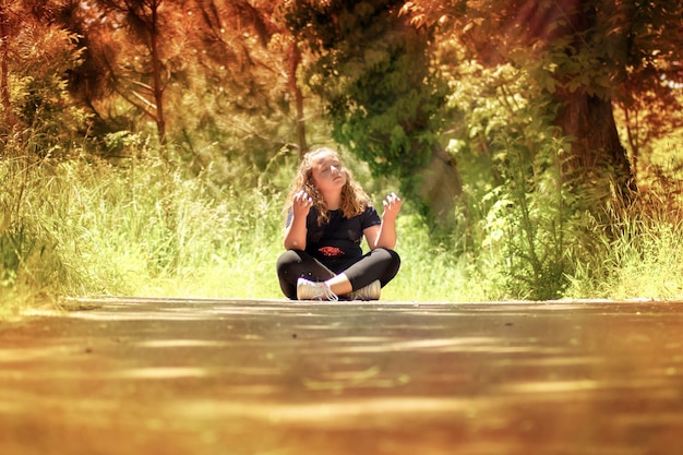 A person sitting cross-legged in a peaceful yoga pose outdoors, surrounded by nature. They are holding their phone, but the screen is turned off. The scene emphasizes mindfulness and taking a break from technology to connect with the physical world.