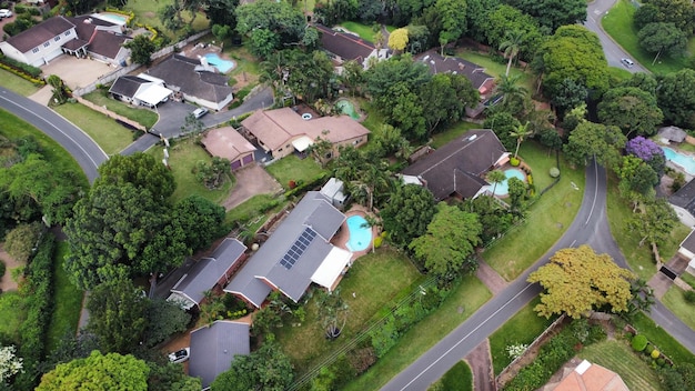 An aerial view of a well-planned suburban community featuring single-family homes with spacious yards, community parks, and walking trails. The scene should depict a balance between residential areas and green spaces, showcasing the attractiveness of suburban living for remote workers and families.