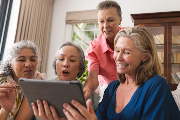A senior woman smiling as she video chats with her family on a tablet. The background shows a cozy living room with comfortable furniture, emphasizing the ease and comfort of using technology to connect with loved ones.