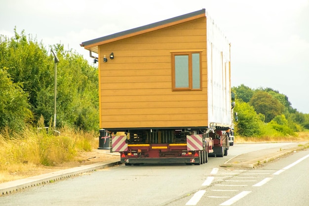 A modular home being transported on a flatbed truck, ready for assembly on-site, illustrating the ease and efficiency of modular home delivery and installation.