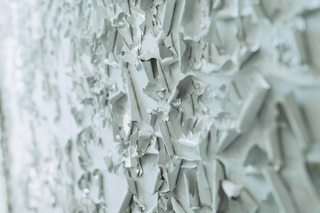 A close-up view of a 3D printing nozzle layering concrete to form the wall of a house. The layers are smooth and even, showing the precision of the technology. Construction workers in safety gear oversee the process.