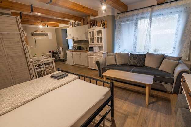 The interior of a tiny house, showcasing a well-organized living space with multi-functional furniture, such as a foldable table, built-in storage, and a compact kitchen area. Natural light streams through a large window, creating a bright and airy atmosphere.