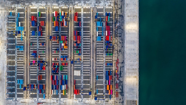 A detailed aerial shot of a bustling port, showcasing container ships being loaded and unloaded, with trucks and trains nearby, illustrating the intermodal nature of freight transportation.